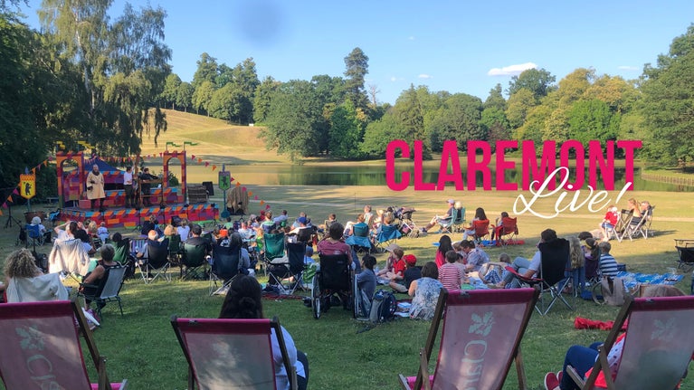 A photography of people gathered around an outdoor theatre stage with Claremont's lake and amphitheatre in the background. The words Claremont Live are written on the left hand side